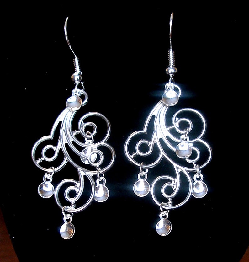 Peut inclure: Boucles d'oreilles pendantes en argent avec un design d&eacute;licat et tourbillonnant et plusieurs petites perles rondes.