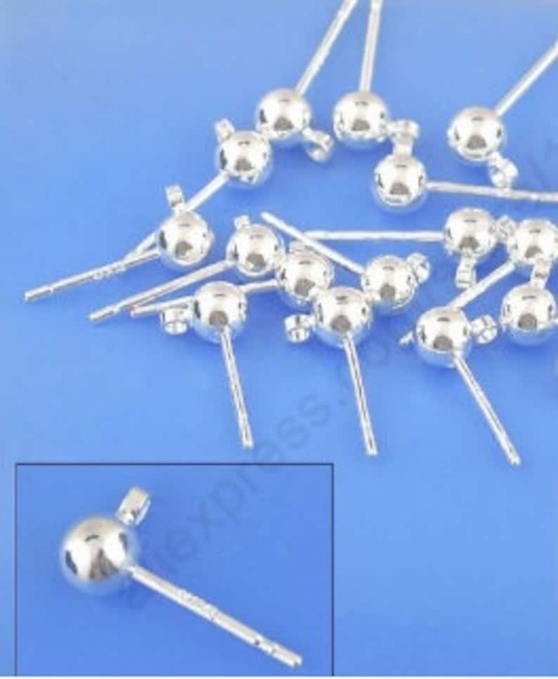 Peut inclure: Gros plan sur un groupe de tiges d'oreille en argent avec des boules rondes au sommet. Les tiges mesurent environ 2,5 cm de long et les boules ont un diam&egrave;tre d'environ 5 mm.