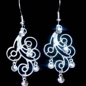 Peut inclure: Une paire de boucles d'oreilles pendantes en argent avec un motif d&eacute;licat et tourbillonnant et de petites perles rondes qui pendent du bas.