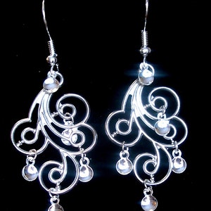 Peut inclure: Boucles d'oreilles pendantes en argent avec un design d&eacute;licat et tourbillonnant et plusieurs petites perles rondes.