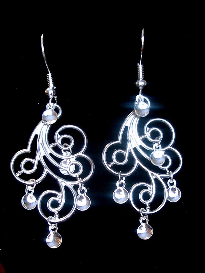 Peut inclure: Boucles d'oreilles pendantes en argent avec un design d&eacute;licat et tourbillonnant et plusieurs petites perles rondes.