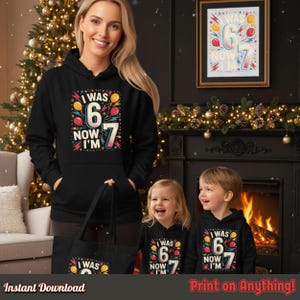 Mother and two children wearing matching “I Was 6 Now I’m 7” hoodies beside a decorated Christmas tree and fireplace. Demonstrates the design’s family-friendly, festive look for all ages.
