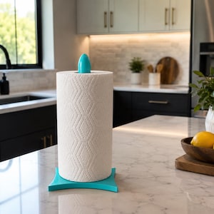 May include: A vertical paper towel holder with a bright turquoise base and a matching turquoise finial at the top. The holder supports a roll of white paper towels featuring a subtle, embossed diamond pattern across the entire surface.