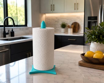 May include: A vertical paper towel holder with a bright turquoise base and a matching turquoise finial at the top. The holder supports a roll of white paper towels featuring a subtle, embossed diamond pattern across the entire surface.