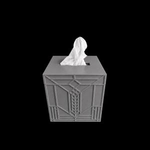 May include: A square, matte gray tissue box cover featuring a raised, geometric, linear relief pattern on its exterior sides. A single white tissue is pulled through the rectangular opening at the top of the box, which is set against a black background.