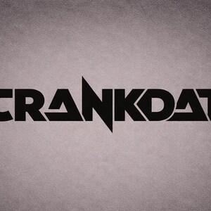 May include: The word "CRANKDAT" is displayed in black, bold lettering against a grey textured backdrop. A sharp, upward-pointing triangle bisects the letter "A". The font is modern and stylized.
