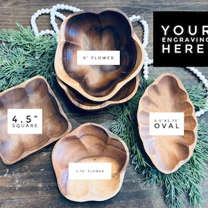 May include: Wooden serving bowls in various shapes: a 4.5-inch square, two flower-shaped bowls (6-inch and 4.75-inch), and a 6.5 x 3.75-inch oval. The bowls are arranged on a wooden surface with greenery and a string of pearls. The text "YOUR ENGRAVING HERE!" is displayed.