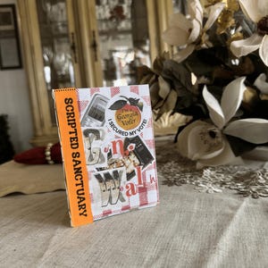 May include: A small, rectangular book with a red and white checkered pattern on the cover. The book has the words "n-o-w-a-l-h" in a collage style. The spine is orange and reads "SCRIPTED SANCTUARY". A sticker on the cover says "I'm a Georgia Voter".
