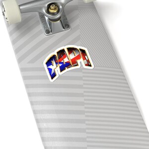 May include: A sticker with the word "PAPI" in red, white, and blue, with a gold outline. The sticker is on a skateboard deck with a gray and white striped pattern. The skateboard's trucks and wheels are visible.