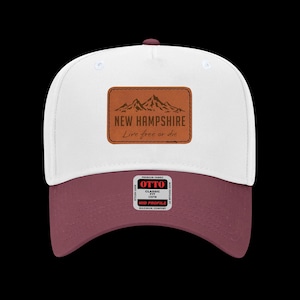 May include: A white and burgundy baseball cap with a curved brim. The cap features a brown leather patch with the text "NEW HAMPSHIRE" and "Live free or die" above a mountain graphic. The cap has a mid-profile fit.
