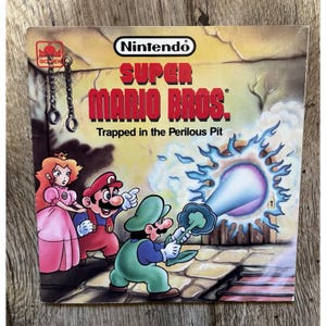 May include: A vintage Super Mario Bros. video game box featuring Mario, Luigi, and Princess Peach. The cover art shows the characters in a perilous pit with the text "Trapped in the Perilous Pit". The Nintendo logo is at the top.