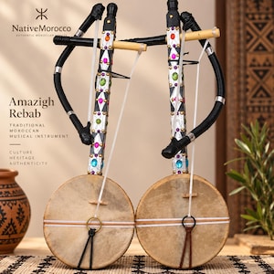 Puede incluir: Dos instrumentos musicales Amazigh Rebab con cuerpos circulares cubiertos de piel, largos mástiles verticales decorados con metal plateado, patrones geométricos negros y piedras de colores incrustadas. Cada instrumento tiene un arco negro curvado.