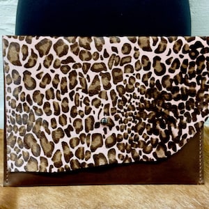 Cartera de mano tipo sobre de piel y pelo de leopardo en marrón y rosa