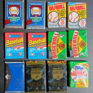 May include: A collection of vintage baseball card packs, including brands like Fleer, Donruss, and Topps. The packs feature colorful designs and the Major League Baseball logo. Some packs are labeled "1989" and "Comeback Edition."
