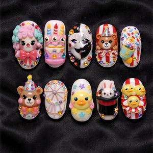 May include: A collection of ten decorative nail art designs. The designs include a clown, a cake, a mask, a bear, a popcorn bucket, a Ferris wheel, a duck, a rabbit in a hat, and two sets of ducklings. Each nail is embellished with colorful gems.