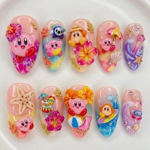 May include: A set of ten artificial nails with a summer theme. Each nail features a different design, including Kirby characters, flowers, starfish, and waves. The nails are painted in various colors, including pink, blue, yellow, and purple.