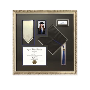 Puede incluir: Un marco de graduación con diploma, foto de graduado, corbata y birrete con borla azul. El marco es dorado y el fondo negro. El texto "Happy graduation!" es visible.