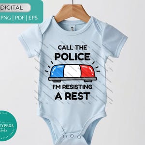 May include: A light blue baby onesie with the text "CALL THE POLICE I'M RESISTING A REST" and a police light graphic. The onesie is hanging on a wooden hanger.