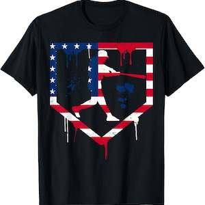 May include: Black t-shirt with a baseball player silhouette inside a home plate shape. The design uses the American flag with red and white stripes, blue stars, and paint drips, giving a patriotic and sporty appearance.