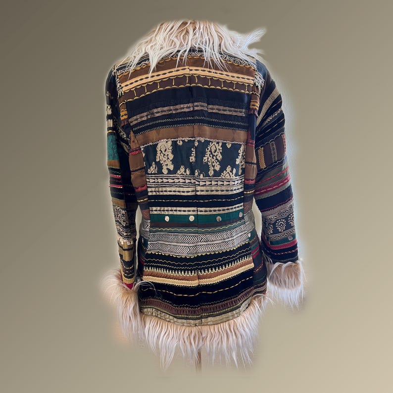 May include: A patchwork coat with a faux fur collar and cuffs. The coat features a variety of patterned fabrics in shades of brown, black, green, and red. The design includes embroidered details and horizontal stripes.