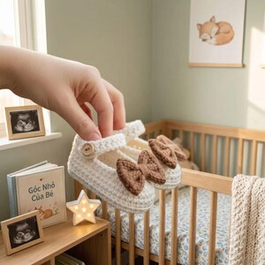 Crochet baby booties styled in nursery setting cream wool Mary Jane shoes with bow soft warm newborn infant gift baby shower idea