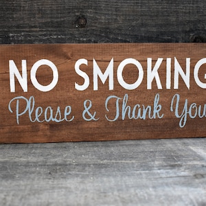 以下が含まれることがあります： 白と青のペンキで「NO SMOKING Please & Thank You」と書かれた素朴な木製の看板です。