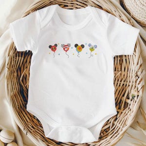 May include: White baby bodysuit with colorful embroidered balloon designs. Each balloon features a Mickey Mouse head and a different design, including a checkered flag and the number 95. The bodysuit is displayed in a woven basket.