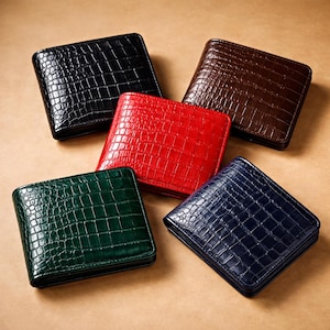 Könnte beinhalten: Fünf Ledergeldbörsen in Schwarz, Braun, Rot, Grün und Marineblau. Jede Geldbörse hat ein strukturiertes Muster in Krokodiloptik und ein zweifach gefaltetes Design. Die Geldbörsen sind auf einer neutralen Oberfläche angeordnet.