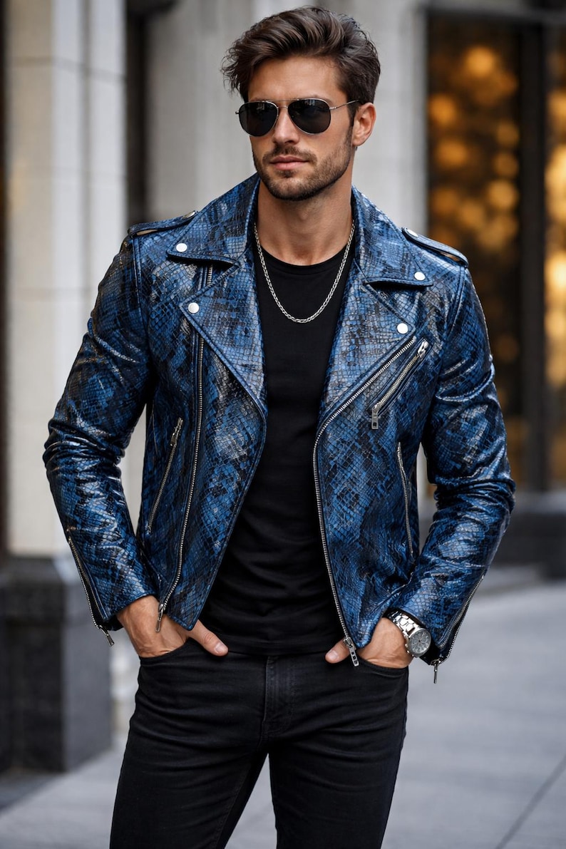 K&ouml;nnte beinhalten: Blaue Lederjacke mit Schlangenmuster, silbernen Rei&szlig;verschl&uuml;ssen und einem Reverskragen. Die Jacke wird &uuml;ber einem schwarzen T-Shirt und mit schwarzen Jeans getragen. Eine silberne Halskette und eine Uhr sind ebenfalls zu sehen.