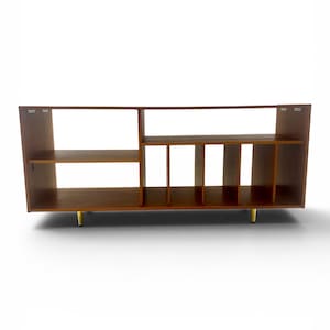 May include: A mid-century modern wooden cabinet with a warm brown finish. The cabinet features open shelving, vertical dividers, and gold-colored legs. The design is symmetrical and the cabinet is suitable for storage.