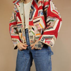 Pu&ograve; includere: Giacca patchwork con un design rosso, bianco e multicolore. La giacca presenta un collo e chiusure con bottoni. Le maniche sono lunghe e la giacca sembra trapuntata.