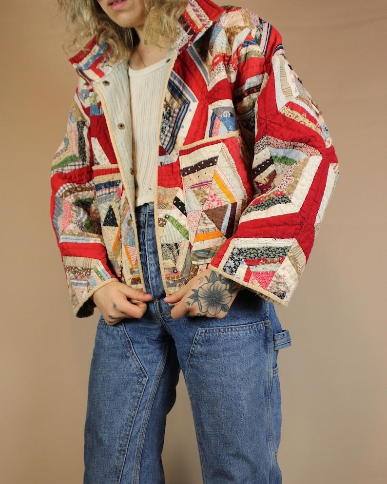 Pu&ograve; includere: Giacca patchwork con un design rosso, bianco e multicolore. La giacca presenta un collo e chiusure con bottoni. Le maniche sono lunghe e la giacca sembra trapuntata.