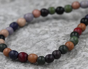 May include: A colorful wooden bead bracelet with beads in shades of brown, green, blue, purple, and red.