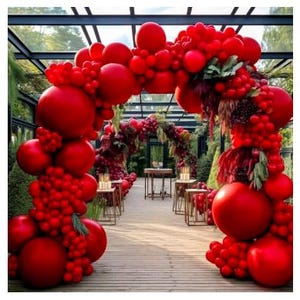 May include: A vibrant red balloon archway, adorned with clusters of smaller red balloons and floral accents, creates a festive entrance. The arch frames a pathway leading to a table setting, suggesting a celebratory event or wedding ceremony. The scene is set outdoors.
