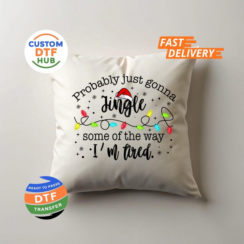May include: Cream-colored square pillow with the text "Probably just gonna Jingle some of the way I'm tired." The text is in black with a Santa hat on the word "Jingle" and a string of Christmas lights.
