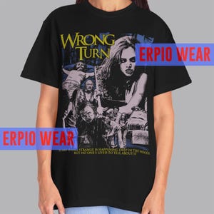 May include: Black t-shirt featuring a graphic from the horror film "Wrong Turn." The design includes the film's title in yellow, a woman, and several figures. The text "Something strange is happening deep in the woods but no one's lived to tell about it" is also present.