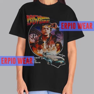 May include: Black t-shirt with a graphic from the film "Back to the Future." The design includes the film's title, characters, and a DeLorean car. The text "WATER IN TIME FOR" and "S TIME AT ALL" is also visible.