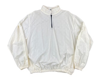 May include: A white long-sleeve pullover jacket featuring a high collar, a dark-colored quarter-zip front closure, and elasticized cuffs and hem. The fabric has a subtle, repeating square grid pattern throughout the entire garment.