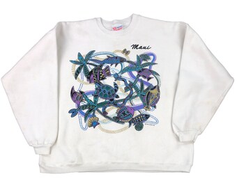 Op de afbeelding: Een wit sweatshirt met lange mouwen en een kleurrijke grafische print van tropische vissen, een zeeschildpad, palmbomen en gestippelde wervelende patronen. Het woord Maui staat in zwarte schrijfletters boven het ontwerp in blauw, paars en geel.