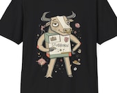 May include: A black short-sleeve t-shirt featuring a graphic illustration of a bull with a nose ring, wearing a box labeled STUBBORN. The bull is surrounded by small decorative icons including flowers, a hand, and a plate of food on a dark background.