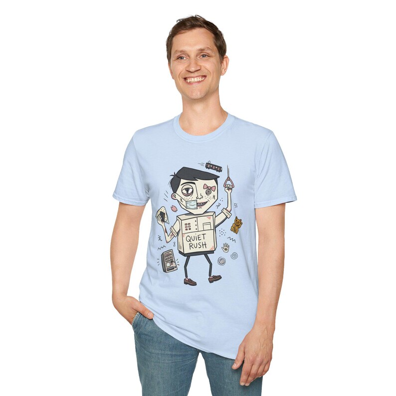 Op de afbeelding: Lichtblauw T-shirt met een cartoon robot ontwerp en de tekst "QUIET RUSH". De robot heeft een doosvormig lichaam, een verband en houdt een metro handvat vast. Andere cartoon elementen zijn een teddybeer en een radio.