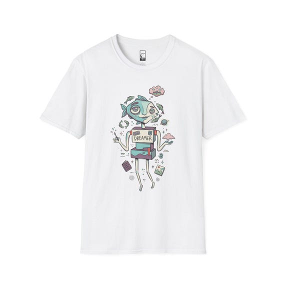 May include: A white short-sleeve t-shirt featuring a graphic illustration of a fish-headed robot character with the word DREAMER printed on its chest. The design includes small floating elements like fish, clouds, a planet, and books in muted colors.