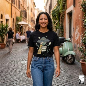 Może przedstawiać: Czarny t-shirt z kresk&oacute;wkowym wzorem kosmity. Kosmita, w szarej czapce statku kosmicznego, trzyma worek z pieniędzmi i dokument z napisem "ABDUCTED". Osoba ma na sobie niebieskie dżinsy.