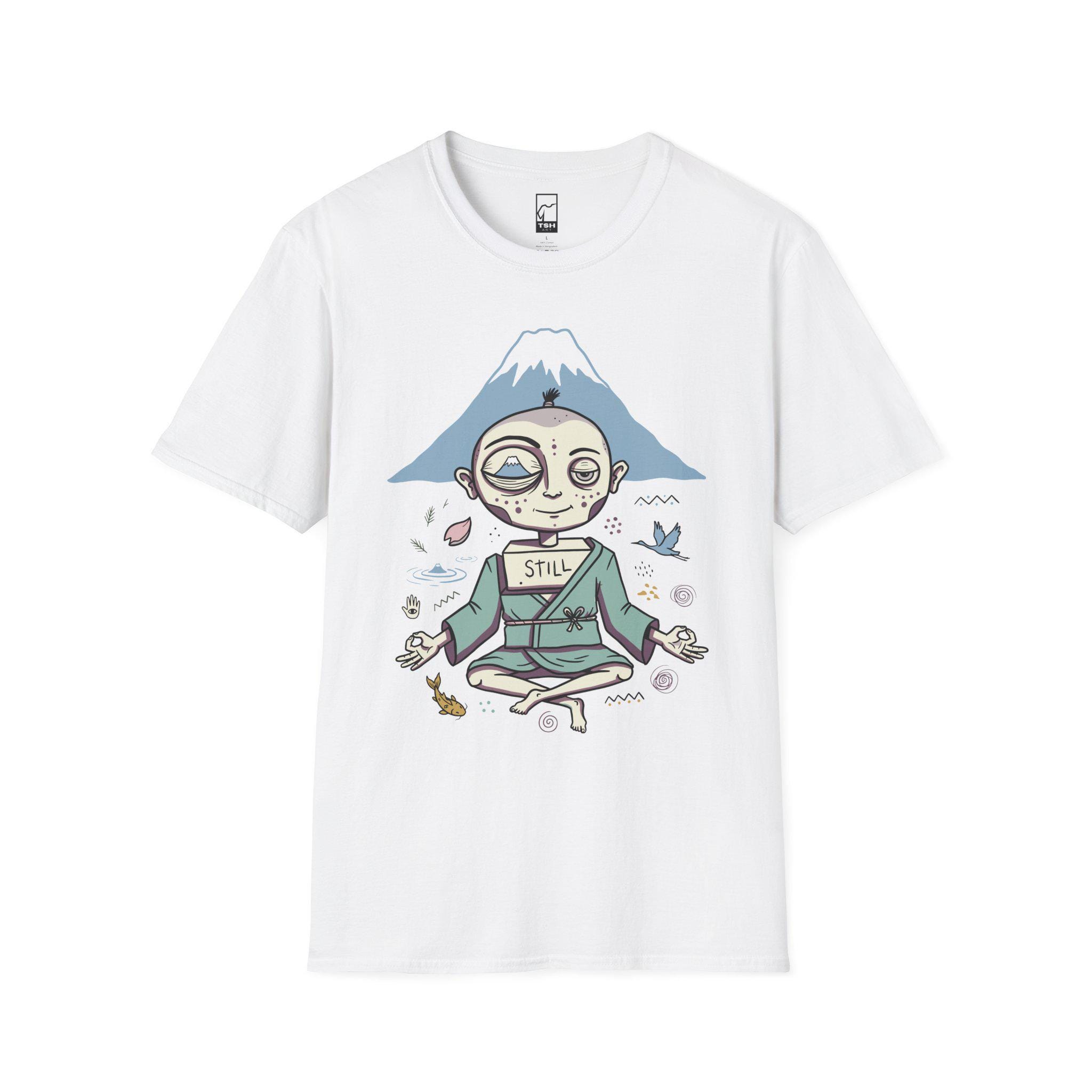 May include: A white short-sleeve t-shirt featuring a graphic of a figure in a teal robe sitting in a meditative pose. The figure has a box on their chest labeled STILL and a mountain in the background with small icons of a fish, bird, and petals.