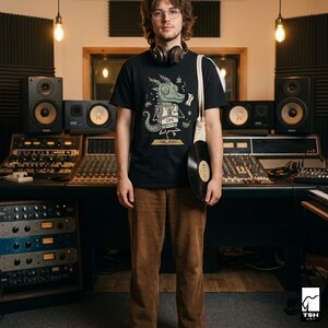 Op de afbeelding: Een zwart t-shirt met een groene drakenafbeelding, bruine corduroy broek en een draagtas met een vinylplaat. De persoon draagt een koptelefoon en een bril. De achtergrond omvat studioapparatuur en geluidsisolatie.