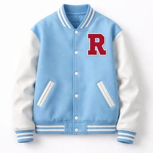 Op de afbeelding: Lichtblauwe varsity jas met witte mouwen en een rode letter "R" patch. De jas heeft een knoopsluiting, wit en blauw gestreepte manchetten en zoom, en witte zakafwerking. Een klassieke, sportieve look.