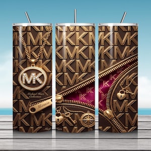 Pode incluir: Um copo cilíndrico com palhinha apresentando um padrão repetitivo de logótipos MK em castanho e dourado. O design inclui um colar dourado com um pendente circular, um fecho com o nome Minnie e berloques em forma de coração e bússola.