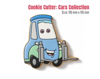 May include: A cookie cutter in the shape of a cartoon forklift truck. The cookie cutter is blue, green, and white with black wheels and a smiling face. The text "Cookie Cutter: Cars Collection" is at the top.