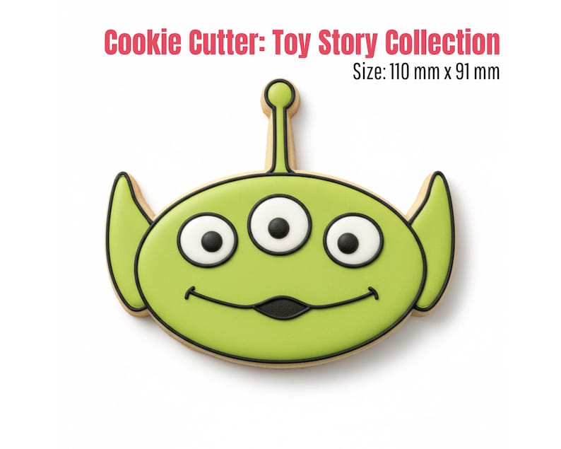 May include: A green cookie cutter in the shape of a three-eyed alien from the Toy Story Collection. The cookie cutter has black outlines and white and black eyes. The text "Cookie Cutter: Toy Story Collection" and "Size: 110 mm x 91 mm" are in the image.