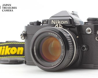 Cámara Nikon FE negra de 35 mm con objetivo Nikkor AI de 50 mm f/1.4 y correa.